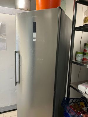 a silver refrigerator in a room with shelves of food