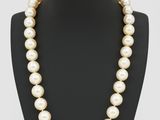 un collier de perles blanches sur un mannequin avec un fermoir en or
