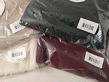 three bags of sweaters sitting on a table next to each other