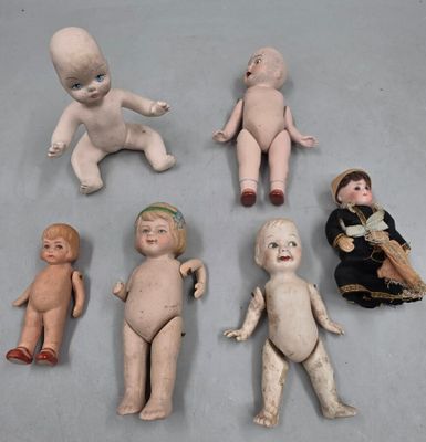 Plusieurs poupées anciennes sont alignées sur une table