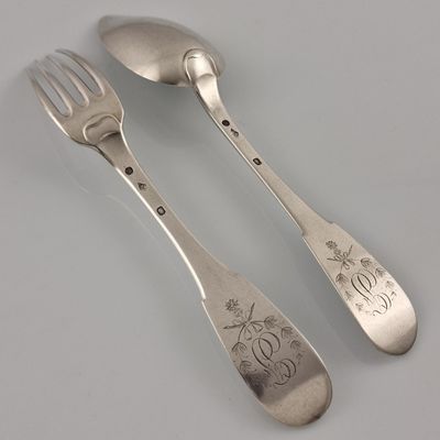 two silver spoons and a fork on a white surface