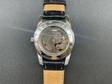 a close up of a watch on a black surface with a brown strap