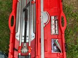 une boîte à outils rouge contenant des outils, posée sur l'herbe