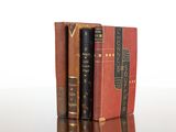 two old books are stacked on top of each other on a table