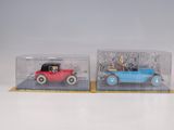 two toy cars in a clear box on a white surface