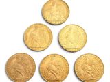 six souverains d'or sont disposés en pyramide sur une surface blanche