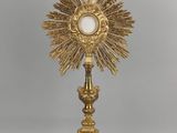 une assiette en or ornée d'une croix, surmontée d'une autre croix
