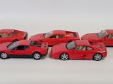 six red toy cars are lined up in a row on a white surface