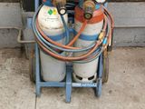 un chariot avec des bouteilles de gaz et un tuyau posé par terre