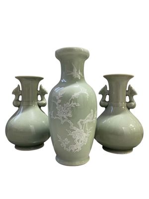 three green vases sitting next to each other on a white surface