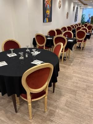 des tables et des chaises disposées dans une longue pièce où est accroché un tableau au mur