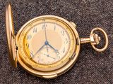 une montre de poche en or posée sur une surface grise