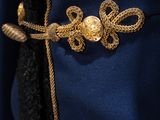 a close up of a blue jacket with a gold broochet