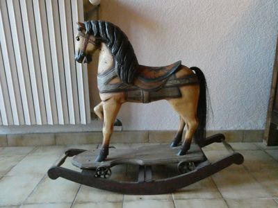 un cheval à bascule en bois posé sur un sol carrelé