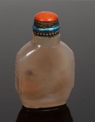 a small glass bottle with a red stone on top