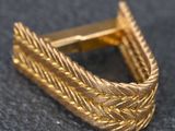 a close up of a gold cuff with a braid design