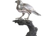 une statue représentant un oiseau perché sur une branche d'arbre