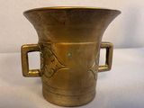 a large brass vase with handles on a table