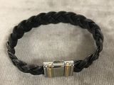 un bracelet en cuir tressé noir muni de deux fermoirs en argent