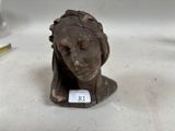 une petite statue représentant une femme, sur laquelle est apposée une étiquette avec son nom