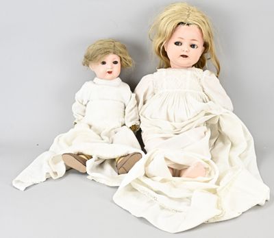 two dolls sitting next to each other on a gray surface