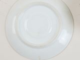 a white plate on a table with a cup and saucer next to it