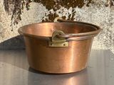 une petite casserole en cuivre posée sur une table en métal