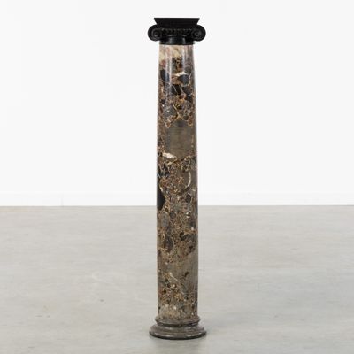 une colonne en marbre noir et blanc surmontée d'un chapiteau noir