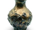 a bronze vase that is sitting on a white surface