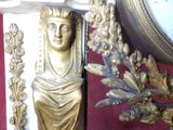 a gold statue of a woman holding a flower next to a clock