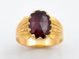 gros plan d'une bague en or avec une pierre rouge