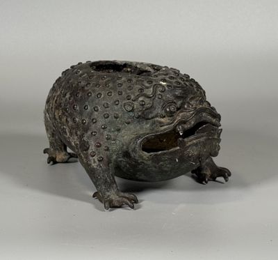 statue en bronze représentant une grenouille assise sur une surface blanche