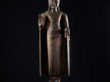 une statue en bronze représentant une personne debout, coiffée d'une couronne