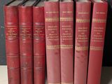 Plusieurs livres rouges sont alignés sur une étagère devant un mur noir.
