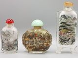 trois flacons à tabac en verre posés les uns à côté des autres sur une surface blanche