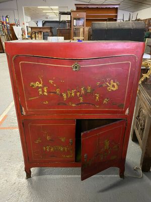 une vieille armoire rouge ornée d'inscriptions en chinois, dans un entrepôt