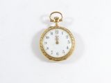 une montre de poche en or avec un cadran blanc sur une surface blanche