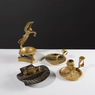 three brass figurines on a white table with a black background