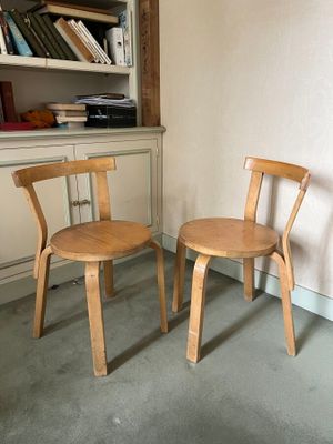 two wooden chairs sitting next to each other in a room