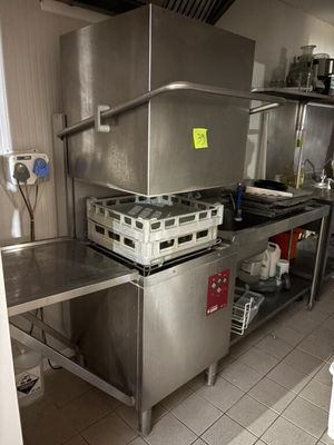 une grande cuisine en inox avec beaucoup de vaisselle sur le plan de travail