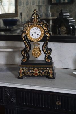 une horloge posée sur une table devant un miroir