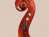 a close up of a violin neck with a fiddle in the background