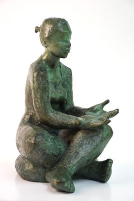 statue d'une femme assise sur un rocher, en train de lire un livre