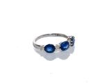 un gros plan d'une bague ornée de pierres bleues sur un fond blanc