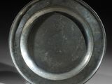 une assiette en argent posée sur une table, sur fond noir