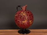 a red vase sitting on top of a wooden table