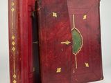 an old book with a red cover and gold decoration on it