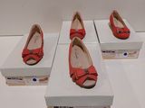 Trois paires de chaussures rouges sont exposées dans une boîte blanche