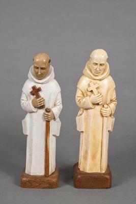 two carved figurines of two men holding a cross and a dog