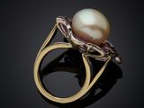 a close up of a pearl and diamond ring on a black surface